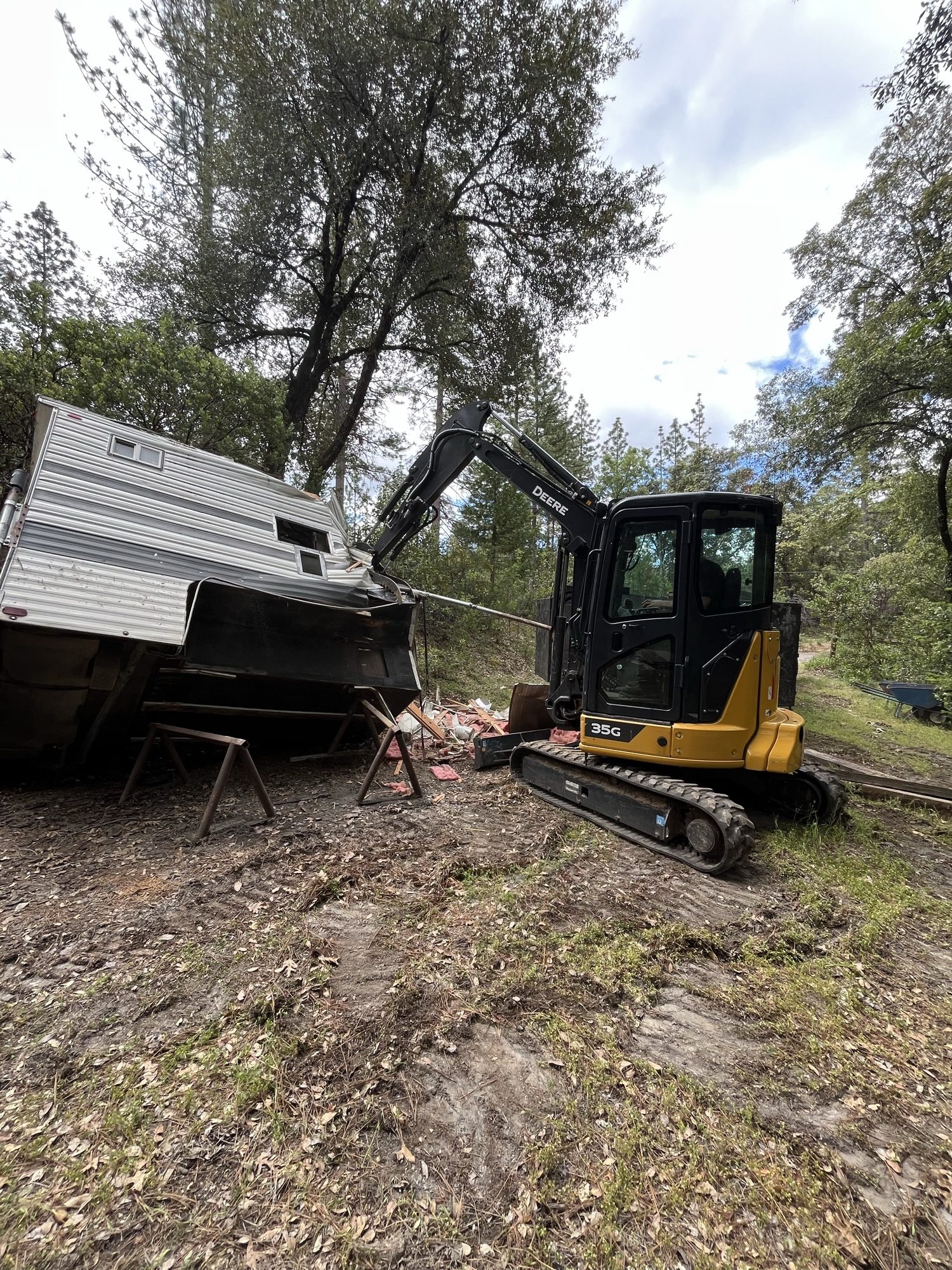 Mini excavator demolishing an old camper during a property cleanout
